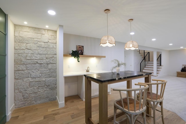 bar with white cabinetry, decorative light fixtures, sink, and light hardwood / wood-style flooring