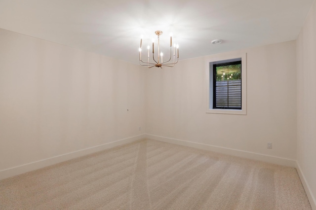 carpeted spare room with an inviting chandelier