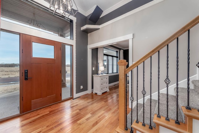 foyer entrance featuring crown molding, a chandelier, and light wood-type flooring