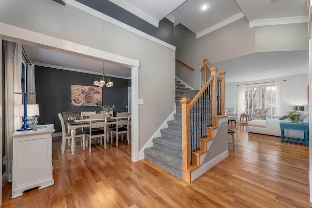 stairs with an inviting chandelier, hardwood / wood-style floors, crown molding, and a towering ceiling