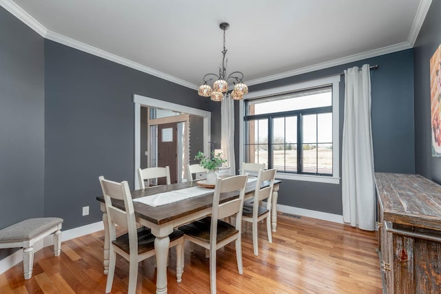 dining space featuring ornamental molding, a notable chandelier, and light hardwood / wood-style floors