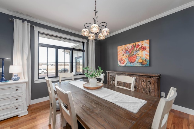 dining area with light hardwood / wood-style flooring, ornamental molding, and a chandelier