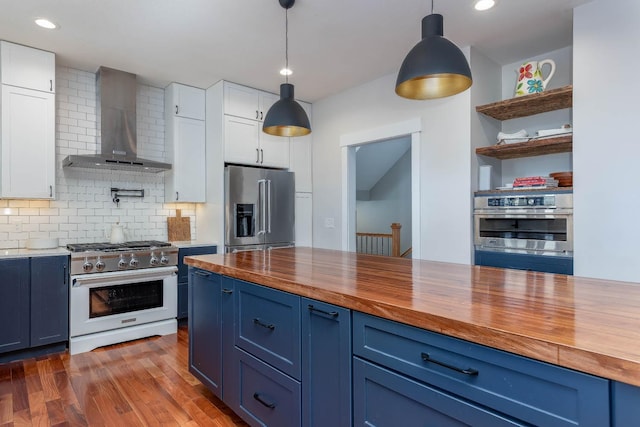 kitchen with high quality appliances, white cabinetry, wood counters, and wall chimney exhaust hood