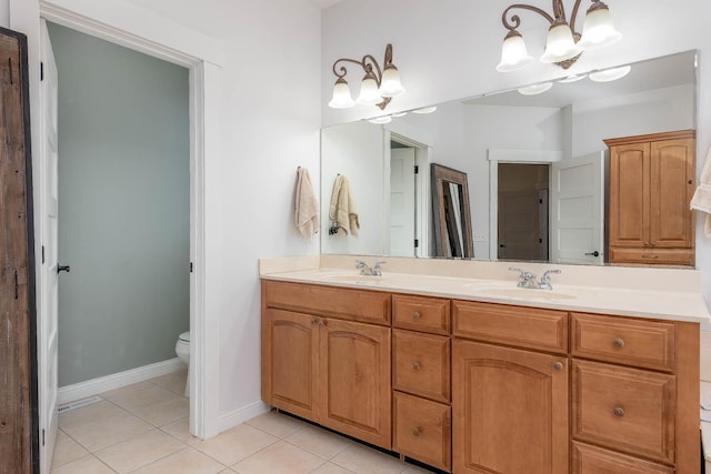 bathroom with tile patterned flooring, vanity, a chandelier, and toilet