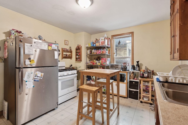 kitchen featuring sink, stainless steel fridge, and white gas range oven