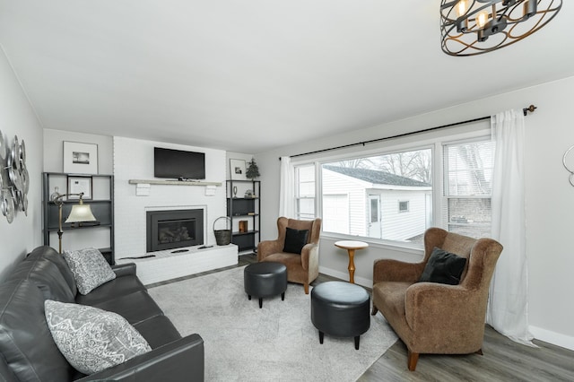 living room with wood-type flooring, a brick fireplace, and a chandelier