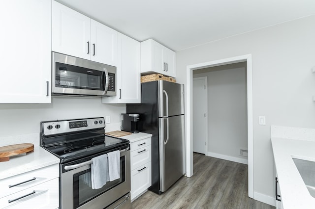 kitchen featuring stainless steel appliances, light stone countertops, white cabinets, and dark hardwood / wood-style flooring