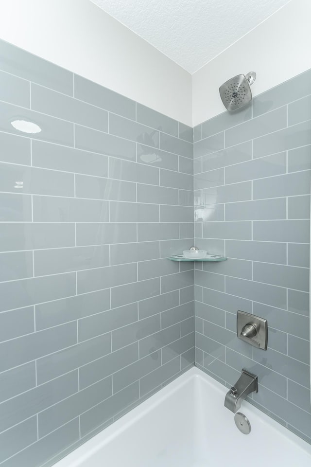 bathroom featuring tiled shower / bath and a textured ceiling