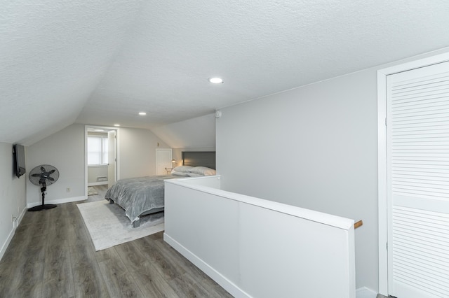 bedroom with vaulted ceiling, a textured ceiling, and dark hardwood / wood-style flooring