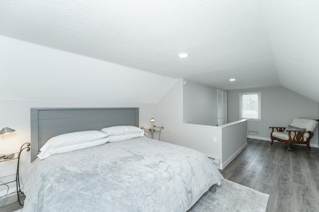 bedroom featuring lofted ceiling, wood-type flooring, a textured ceiling, and a baseboard heating unit