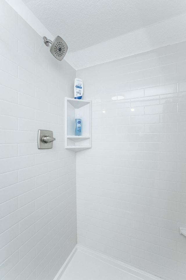 bathroom with a tile shower and a textured ceiling