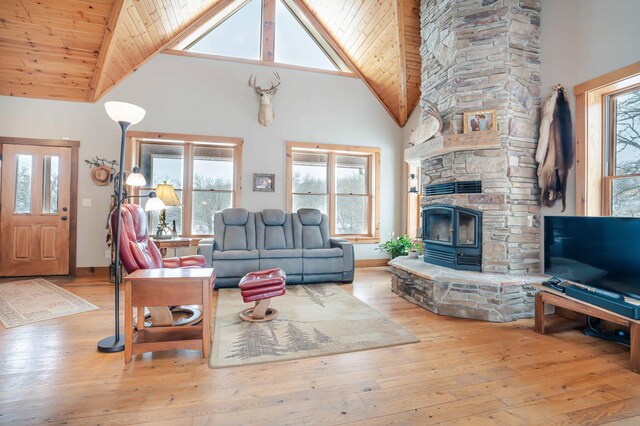 living room with wood ceiling, a stone fireplace, and light wood-type flooring