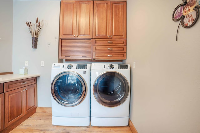 laundry area with cabinets, independent washer and dryer, and light hardwood / wood-style floors