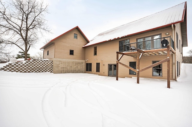 snow covered rear of property with a balcony