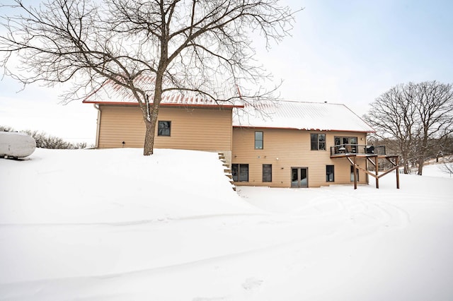 snow covered back of property with a deck