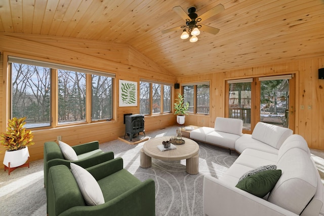 living room featuring lofted ceiling, wooden walls, wooden ceiling, and a wood stove