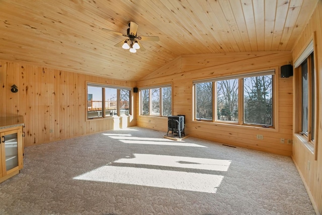 interior space with vaulted ceiling, a wood stove, and wood walls