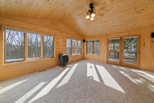 unfurnished sunroom with lofted ceiling, wood ceiling, ceiling fan, and a wood stove