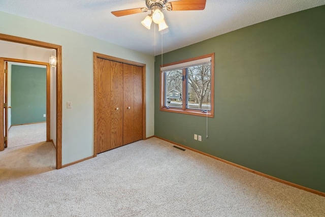 unfurnished bedroom with carpet floors, a textured ceiling, ceiling fan, and a closet