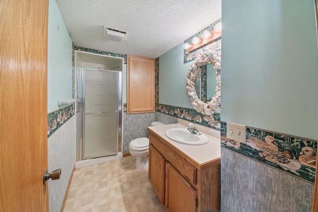 bathroom featuring toilet, vanity, a textured ceiling, and walk in shower