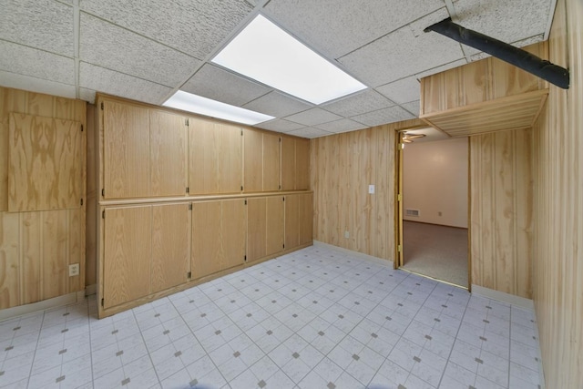 basement with a paneled ceiling and wooden walls