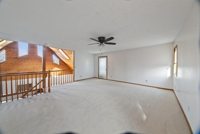 carpeted empty room with ceiling fan and wood walls