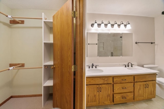 bathroom featuring vanity, toilet, an enclosed shower, and a textured ceiling