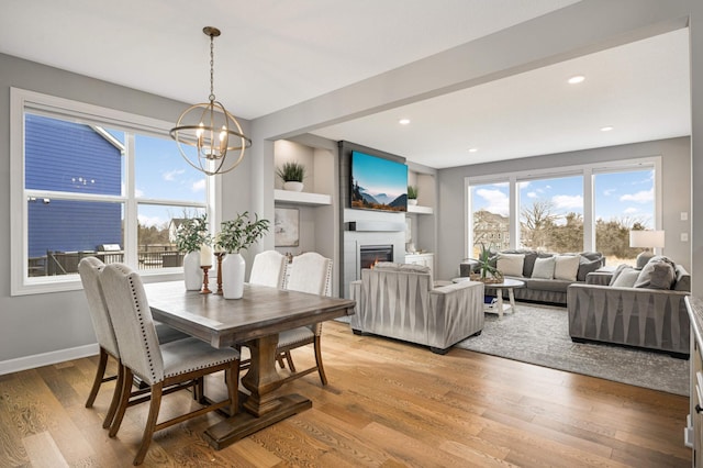 dining space with recessed lighting, an inviting chandelier, a large fireplace, light wood-type flooring, and baseboards