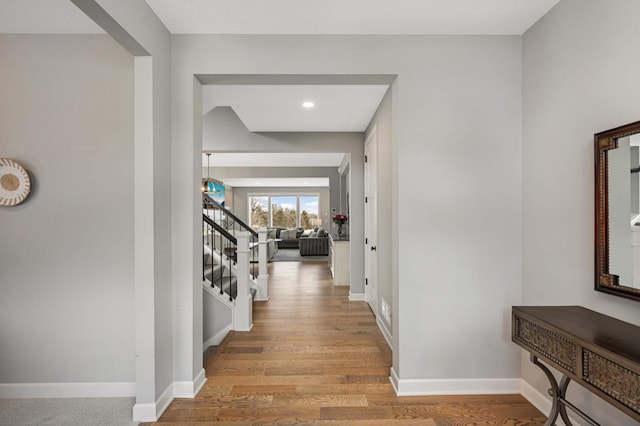 hall with light wood finished floors, baseboards, and stairs