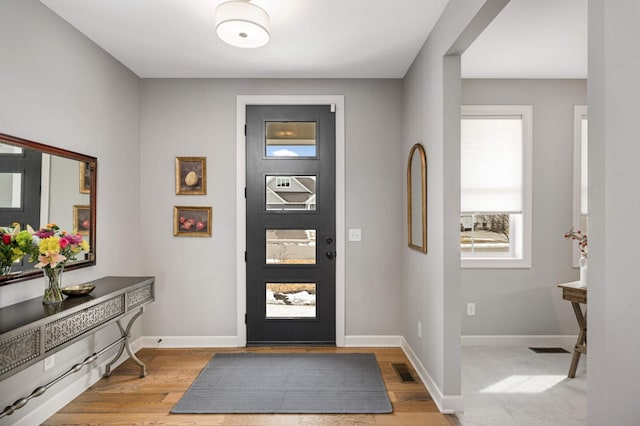 foyer entrance featuring light wood-type flooring, visible vents, and baseboards