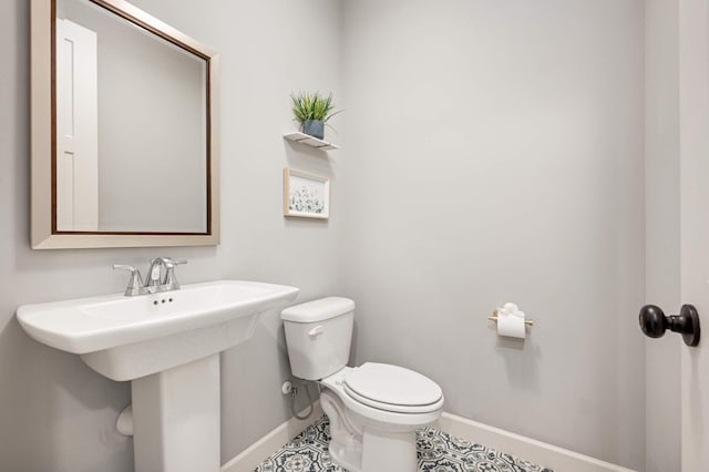 half bathroom featuring a sink, toilet, and baseboards