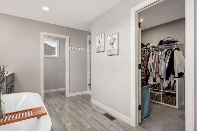 bathroom featuring a freestanding tub, visible vents, baseboards, a spacious closet, and a shower stall