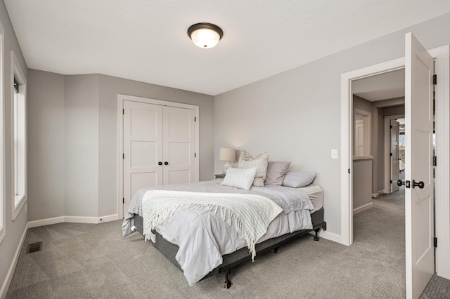 bedroom featuring baseboards, visible vents, a textured ceiling, carpet flooring, and a closet