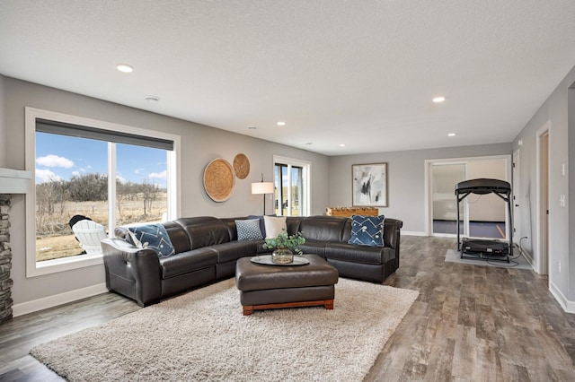 living room with a textured ceiling, recessed lighting, wood finished floors, and baseboards