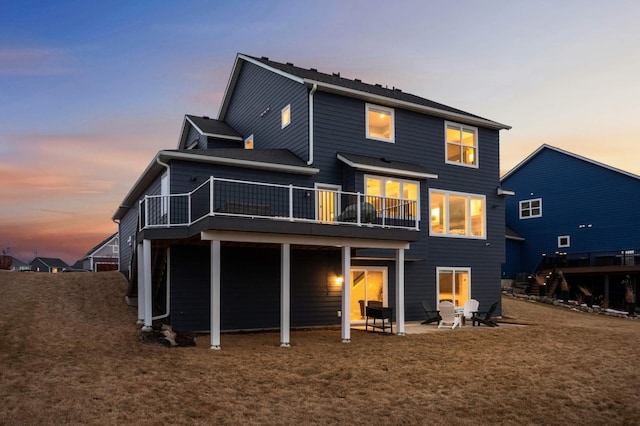 back of property at dusk featuring a patio and a wooden deck