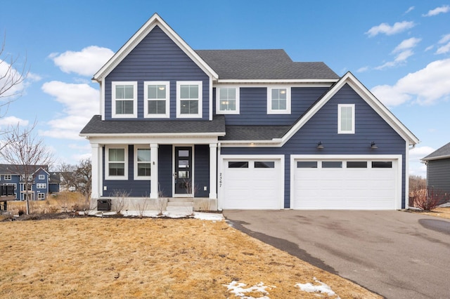 traditional home featuring a garage, driveway, and a shingled roof