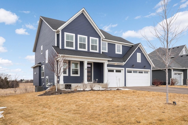 traditional-style house featuring roof with shingles, central air condition unit, an attached garage, driveway, and a front lawn