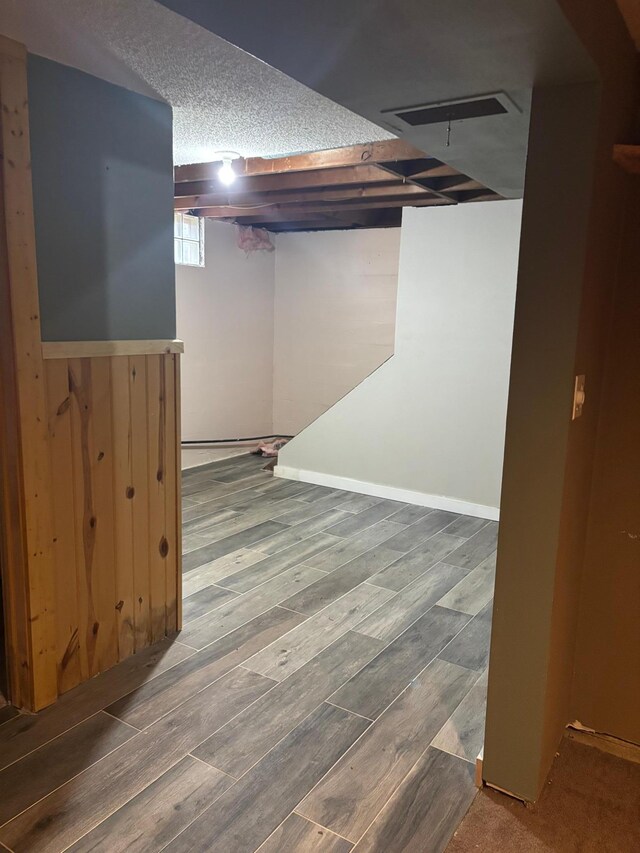 basement featuring a textured ceiling, visible vents, and wood finished floors