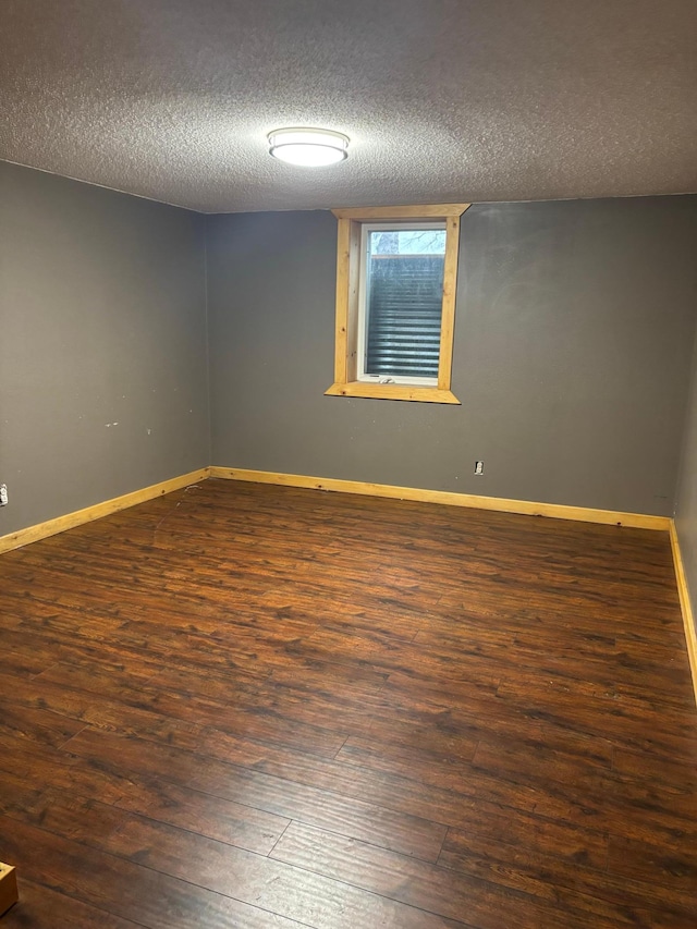 spare room featuring a textured ceiling, baseboards, and hardwood / wood-style flooring