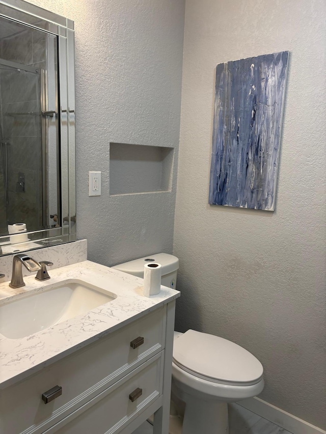 full bathroom with toilet, a textured wall, a shower with shower door, and vanity