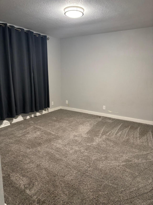 unfurnished room with carpet flooring, a textured ceiling, and baseboards