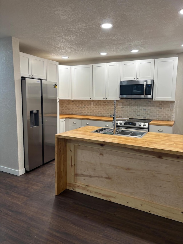 kitchen with stainless steel appliances, dark wood-type flooring, a sink, and wood counters