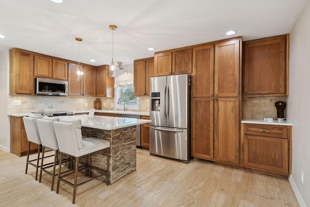 kitchen featuring a breakfast bar, appliances with stainless steel finishes, hanging light fixtures, backsplash, and a center island