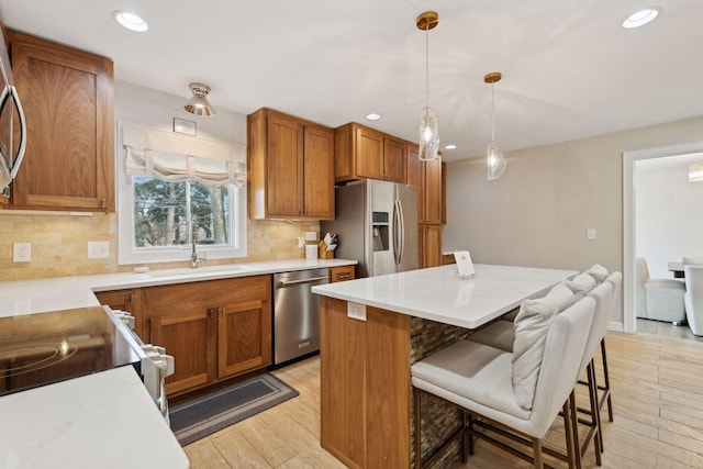 kitchen with sink, decorative light fixtures, light hardwood / wood-style flooring, a kitchen breakfast bar, and stainless steel appliances