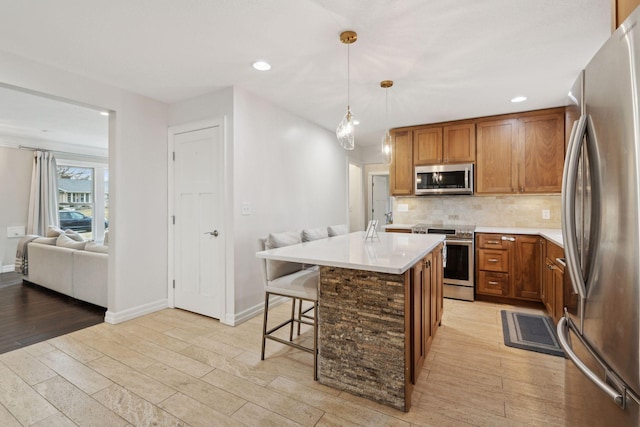 kitchen featuring a breakfast bar, appliances with stainless steel finishes, a center island, decorative backsplash, and decorative light fixtures