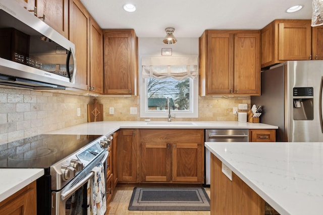 kitchen with sink, appliances with stainless steel finishes, light stone countertops, light hardwood / wood-style floors, and decorative backsplash