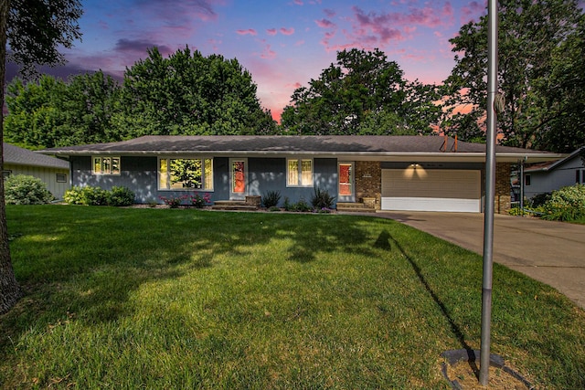 ranch-style house with a garage and a lawn