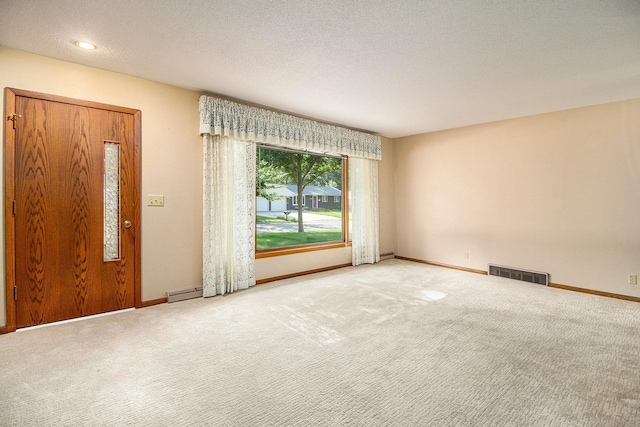 carpeted empty room with a textured ceiling and baseboard heating