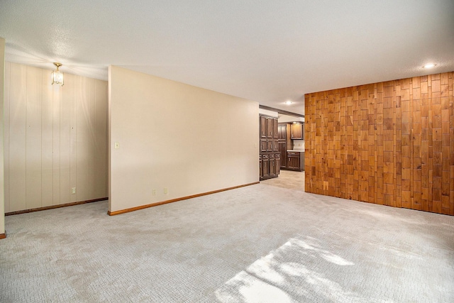 unfurnished room with wooden walls and light colored carpet