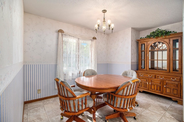 dining space with an inviting chandelier, a textured ceiling, and light tile patterned floors